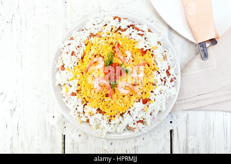 Geschichteten Salat mit Lachs, Tintenfisch, Garnelen, Avocado, Reis und Eiern in einer Platte vor dem Hintergrund der hölzernen Planken an der Spitze Stockfoto