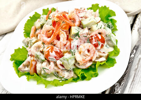 Salat mit Garnelen, Avocado, Tomaten und Mayonnaise auf den grünen Salat in der Platte, Serviette, Gabel auf der Hintergrund-Tisch aus Holz Stockfoto