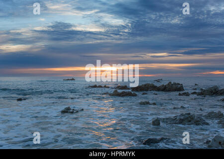 Kaikoura, Neuseeland. Blick über den Pazifischen Ozean aus Felsenküste bei Sonnenaufgang, goldenes Licht spiegelt sich im Wasser. Stockfoto