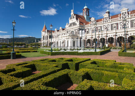 Dunedin, Otago, Neuseeland. Blick über gestutzten Hecken in Anzac Square zur dekorativen Fassade von Dunedin Railway Station. Stockfoto