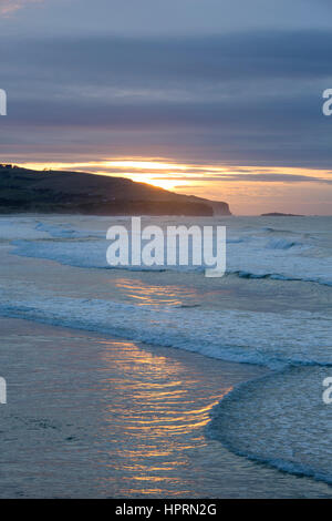 Dunedin, Otago, Neuseeland. Blick über den Pazifik vor St Clair Beach bei Sonnenaufgang, goldenes Licht spiegelt sich im Wasser. Stockfoto