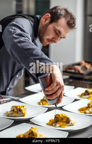 Koch Veredelung seinen Teller und am Tisch fast servierfertig Stockfoto