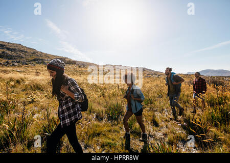 Gruppe von Jugendlichen auf Land zu Fuß. Junge Männer und Frauen wandern an einem Sommertag. Stockfoto