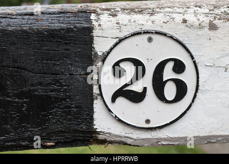 Die Zahl 26 schwarz auf weiß in einem kreisförmigen Rand gemalt Hintergrund weiß und schwarz aus Holz. Stockfoto