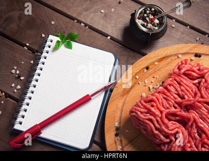 rohes Hackfleisch und leeren Notizblock auf rustikalen hölzernen Hintergrund, Ansicht von oben Stockfoto