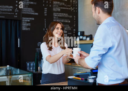 Jungen Barista Kaffee an männlichen Kunden im Café serviert Stockfoto