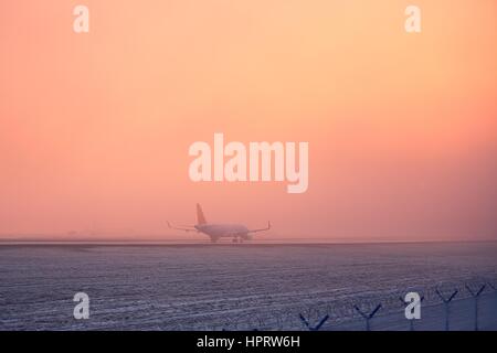 Einfrieren von Nebel am Flughafen. Flugzeug beim goldenen Sonnenuntergang ausziehen. Stockfoto