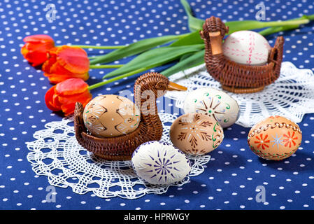 Ostereier und Tulpen auf der blauen Tischdecke Stockfoto