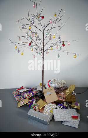 Nicht traditionelle Weihnachtsbaum mit Haufen von Geschenken unten. Stockfoto