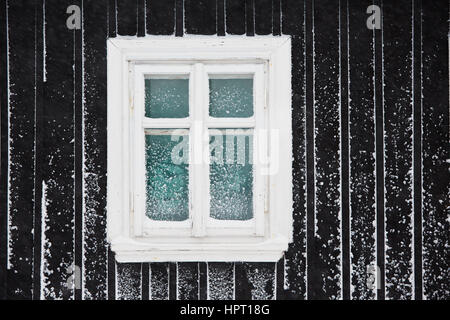 Einzelnes Fenster des Holzhauses im winter Stockfoto
