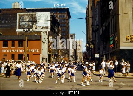 Ein Drill Team bestehend aus Kindern in blauen und weißen Uniformen marschiert nach unten Locust Street während einer Memorial Day Parade in der Innenstadt von St. Louis, Missouri, 28. Mai 1956. Gebäude einschließlich Avis ein Auto mieten, das katholische Information Center, die Farm und Hause Einsparungen und Loan Association Building, und Scruggs Vandervoort Barney Anhang (jetzt auf dem National Register of Historic Places). Stockfoto