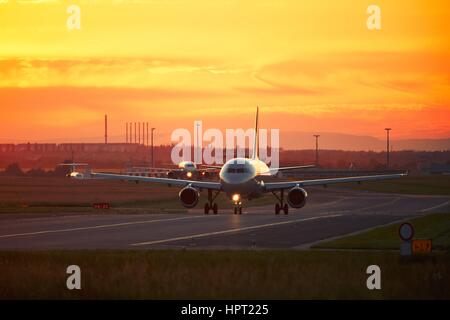 Flughafen-Verkehr bei der goldenen Sonnenuntergang. Flugzeuge sind zur Startbahn für Take off Rollen. Stockfoto