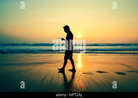 Silhouette des jungen Mannes am Strand bei Sonnenuntergang Stockfoto