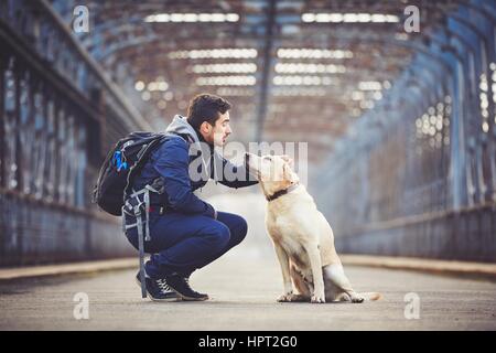 Mann mit seinem gelben Labrador Retriever auf der alten Brücke Stockfoto