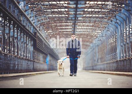 Mann geht mit seinem gelben Labrador Retriever auf der alten Brücke Stockfoto