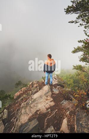 Herbstmorgen. Reisende (Wanderer) oben auf Felsen über dem Flusstal mit dichtem Nebel. Stockfoto