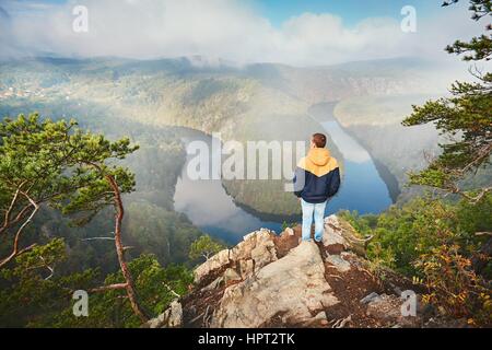 Reisende auf der Oberseite Rock. Junger Mann Aussicht auf Flusstal im Morgennebel. Vltava (Moldau) in Mittelböhmen, Tschechien. Stockfoto