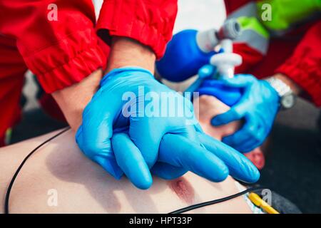 Kardiopulmonalen Reanimation. Rettungs-Team (Arzt und Sanitäter) Wiederbelebung der Mann auf der Straße. Stockfoto