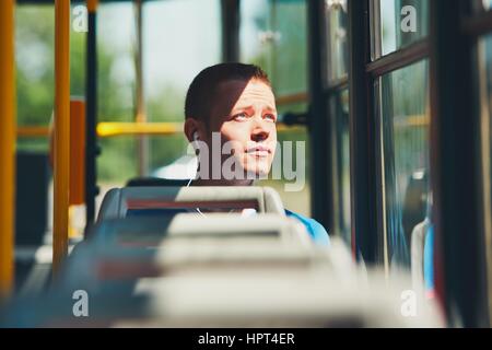 Alltag und pendeln zur Arbeit mit öffentlichen Verkehrsmitteln. Hübscher junger Mann ist mit der Straßenbahn unterwegs. Stockfoto
