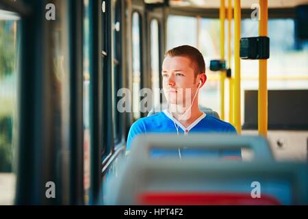Einsamkeit-Mann trägt Kopfhörer und Musik hören. Alltag und pendeln zur Arbeit mit öffentlichen Verkehrsmitteln. Hübscher junger Mann ist trave Stockfoto