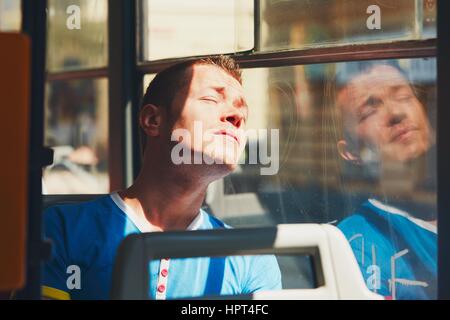 Alltag und pendeln zur Arbeit mit öffentlichen Verkehrsmitteln. Hübscher junger Mann reist mit der Straßenbahn (Bus). Müde Menschen in heißen Tag. Prag, Tschechische Repub- Stockfoto