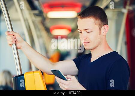 Alltag und mit dem Bus (Straßenbahn) zur Arbeit pendeln. Gut aussehender Mann zahlt Verkehrsticket mit Handy. Stockfoto