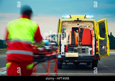 Ärztlicher Notdienst. Sanitäter zieht Bahre mit Patienten zum Krankenwagen Auto. Stockfoto