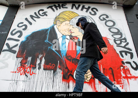 Bristol, UK. 24. Februar 2017. Ein Mann abgebildet ist, ein neues Stück von street Art Warnung über den Tod des NHS vorbeigehen. Das Kunstwerk erschien Teil des Protestes gegen Mittelkürzungen für die NHS "Speichern des NHS" in den letzten Tagen im Bereich Stokes Croft der Stadt. Das Bild zeigt Ministerpräsident Mai und Präsident Trump küssen und warnt davor, dass eine zu enge Beziehung zwischen den beiden Ländern nach Austritt das Ende des NHS ankündigen könnte. Bildnachweis: Lynchpics/Alamy Live-Nachrichten Stockfoto