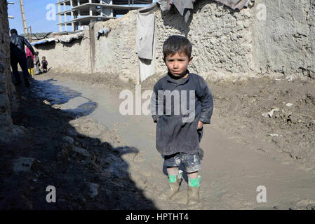 Kabul, Afghanistan. 23. Februar 2017. Ein Junge steht auf dem schlammigen Weg unter den Schlamm Gebäuden im nördlichen Stadtteil von Kabul, Afghanistan, am 23. Februar 2017. Winter hat fast bedeckt, Afghanistan, Auswirkungen auf das Leben der armen Familien, vor allem diejenigen, die keine Erwärmung Ausrüstung, sauberes Wasser oder genug zu essen, mit dem kalten Wetter zu bewältigen haben. In den nördlichen Stadtteil von Kabul viele Leben noch immer in Schlamm Gebäuden und haben kein Geld zum Kauf von Holz, Feuer. Bildnachweis: Dai He/Xinhua/Alamy Live-Nachrichten Stockfoto