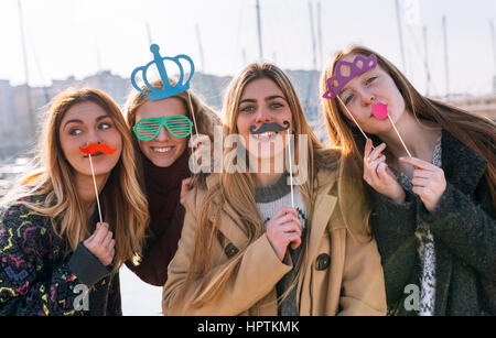Gruppenbild der vier Freunde mit Spielzeug Schnurrbärte, Sonnenbrillen und Kronen Stockfoto