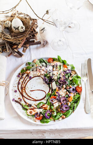 Bunte Salatplatte mit geräuchertem Lachs, Crema di Balsamico und Haselnussöl am gedeckten Tisch Stockfoto