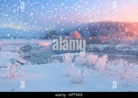 Hellen Weihnachtsmorgen mit Schneefall. Schneeflocken fallen auf schneebedeckten Feld. Winter-Weihnachts-Thema. Stockfoto