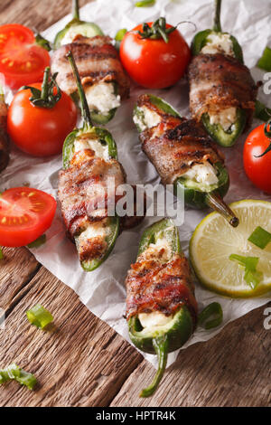 Jalapenopfeffer eingewickelt in Speck und gefüllt mit Frischkäse-close-up auf dem Tisch. vertikale Stockfoto