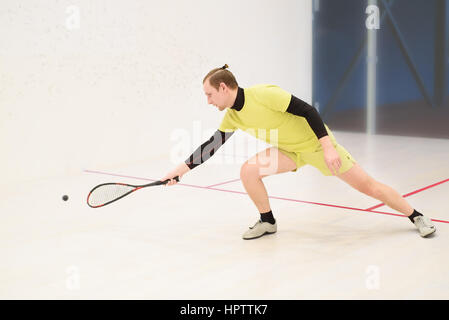 junge kaukasischen Squashspieler Kollision mit einem Ball in einen Squash-Court. Squashspieler in Aktion. Mann Spiel Match Squash. Squash-Sportaktivitäten Stockfoto