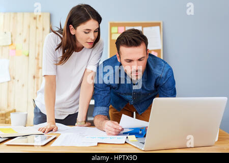 Paar zusammen in kleinen Büros arbeiten mit Notebook und Unterlagen Stockfoto