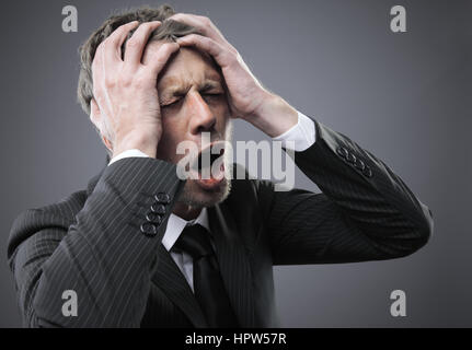 Eine schreiende besorgt, deprimiert und gestresst Geschäftsmann hält seinen Kopf Stockfoto