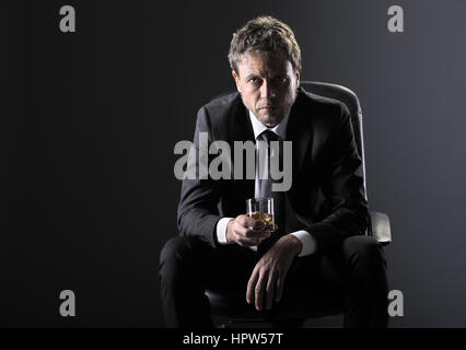 Hübscher Mann mittleren Alters mit einem Glas Whisky Stockfoto