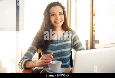 Fröhliches schöne Mädchen im Café einen Kaffee und einen Laptop verwenden Stockfoto