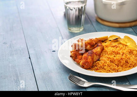 Jollof Reis mit Huhn und gebratenen Kochbananen, westafrikanische Küche Stockfoto