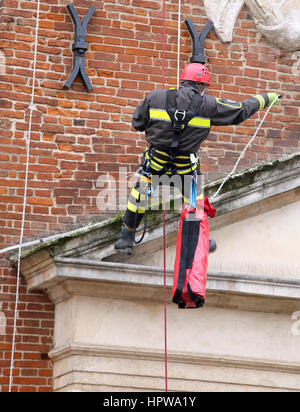 tapfere Feuerwehrmänner mit Seilen klettern und Klettergeräten auf ein altes Gebäude zur Überwachung der Stabilität nach Erdbeben Stockfoto