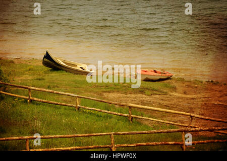 zwei Boote und Holzzaun im Strandbad, Vintage Grunge-Stil Stockfoto