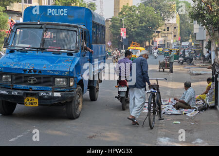 Eine nicht identifizierte Zeitungsverkäufer mit einer Steigung auf einer belebten Straße in Ahmedabad, Indien, mitten in den frühen Morgen-Verkehr Stockfoto