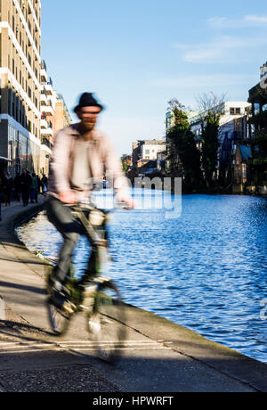 Der bärtige Mann mit dem Hut und einem Fahrrad auf dem Leinpfad des Regent's Canal, London, UK, verschwommen mit Bewegung Stockfoto