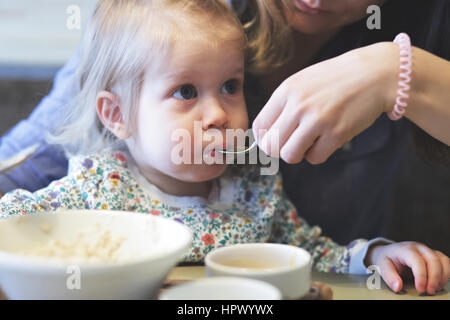 Mutter füttert Brei ihr Kind mit einem gesunden Frühstück Stockfoto