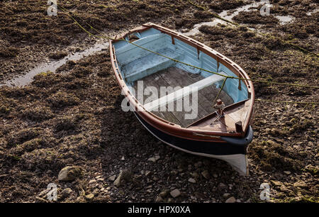 Alte hölzerne Ruderboot gefesselt an den niedrigen Gezeiten. Fishguard Hafen, Pembrokeshire, Wales Stockfoto