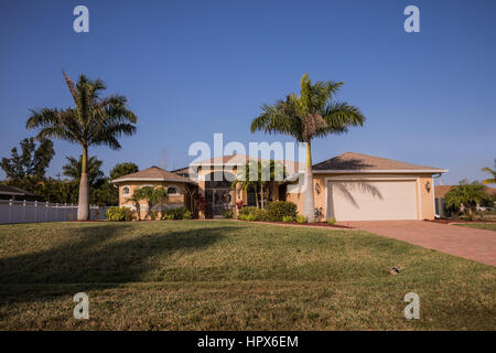 Typische Südwesten Florida Betonblock und Stuck Home in der Landschaft mit Palmen, tropischen Pflanzen und Blumen, Rasen und Pinien. f Stockfoto