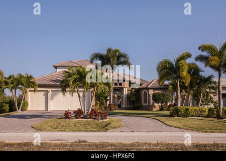 Typische Südwesten Florida Betonblock und Stuck Home in der Landschaft mit Palmen, tropischen Pflanzen und Blumen, Rasen und Pinien. f Stockfoto