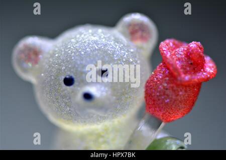 Glas-Teddybär hält eine rote Blume Stockfoto