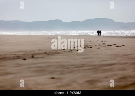 Ein paar mit dem Kinderwagen zu Fuß entlang der menschenleeren Strand von Newborough auf Anglesey, Wales Stockfoto