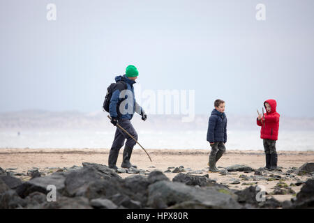Familie auch Vater und zwei Söhne ein Strandleben genießen gehen im Winter auf Newborough Strand auf die Isle of Anglesey, Wales, UK Stockfoto
